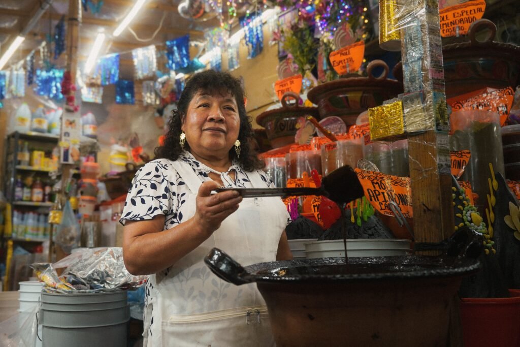 Comerciante mexicana en su puesto de mercado artesanal sonriendo detrás del mostrador.