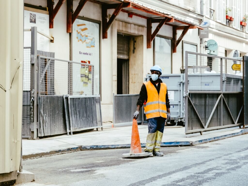 Trabajador con chaleco reflectante de seguridad y mascarilla en una zona urbana de Francia.